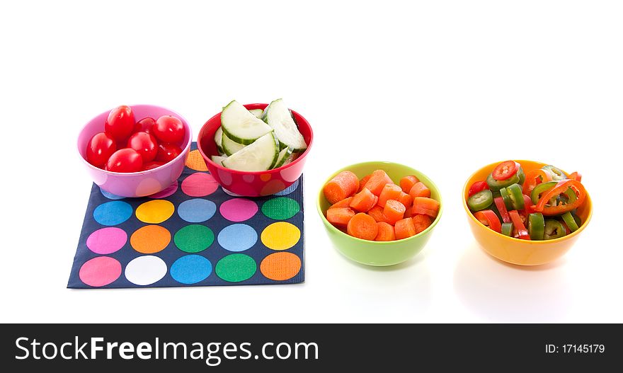 Cut vegetables in colorful plastic bowls isolated over white. Cut vegetables in colorful plastic bowls isolated over white