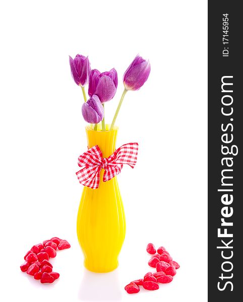 Purple tulips in a yellow little vase decorated with stones isolated over white. Purple tulips in a yellow little vase decorated with stones isolated over white