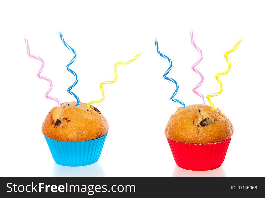 Two colorful muffins decorated with festive candles isolated over white