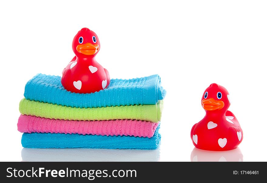 Lovely red ducks on a stack of colorful towels isolated over white. Lovely red ducks on a stack of colorful towels isolated over white