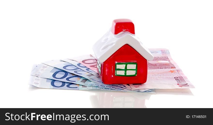 Colorful little house on top of bank notes isolated over white. Colorful little house on top of bank notes isolated over white