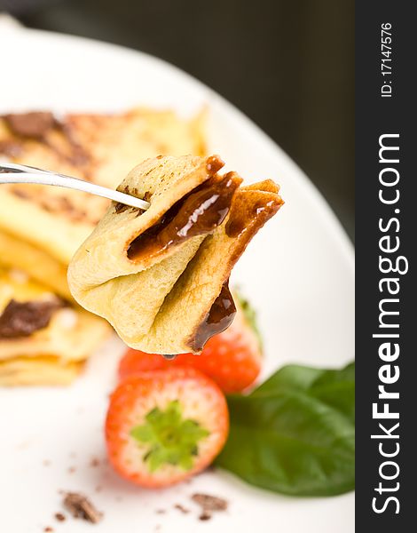 Photo of crepes with choccolate and strawberries on a white plate