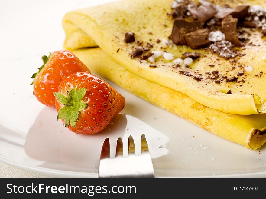 Photo of crepes with choccolate and strawberries on a white plate