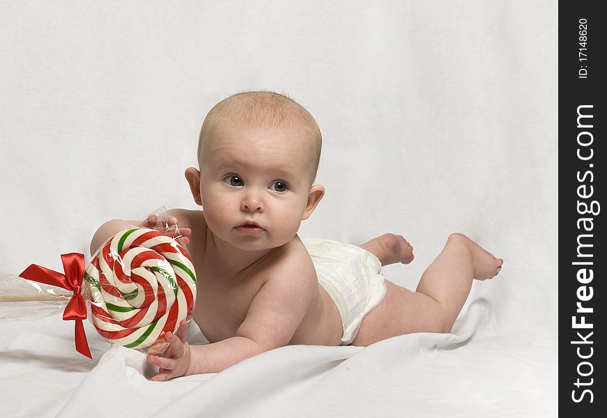 Baby on Tummy, playing with a Candy Cane Lollipop. Baby on Tummy, playing with a Candy Cane Lollipop