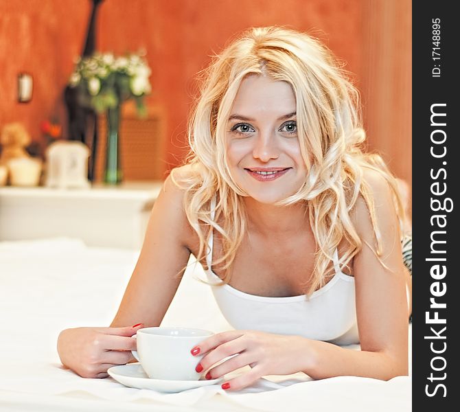 Portrait Of Beautiful Young Woman With Cup On Bed