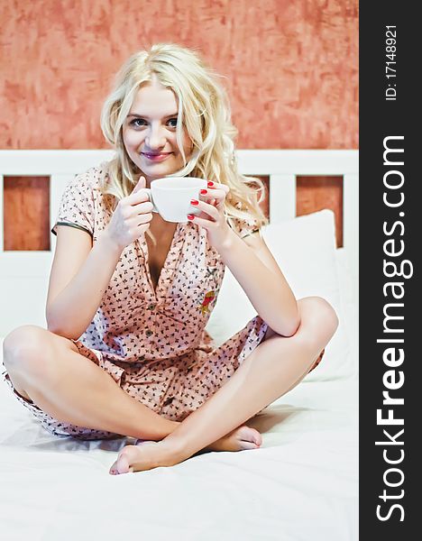 Portrait Of Beautiful Young Woman With Cup On Bed