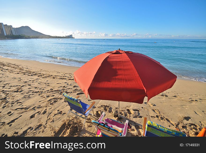 Red umbrella in beach with chairs by ocean