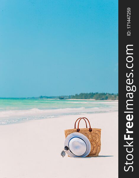 Beach accessories - bag, straw hat, sunglasses on white beach. Beach accessories - bag, straw hat, sunglasses on white beach