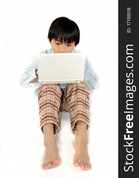 A boy is concentrated on typing his white laptop.