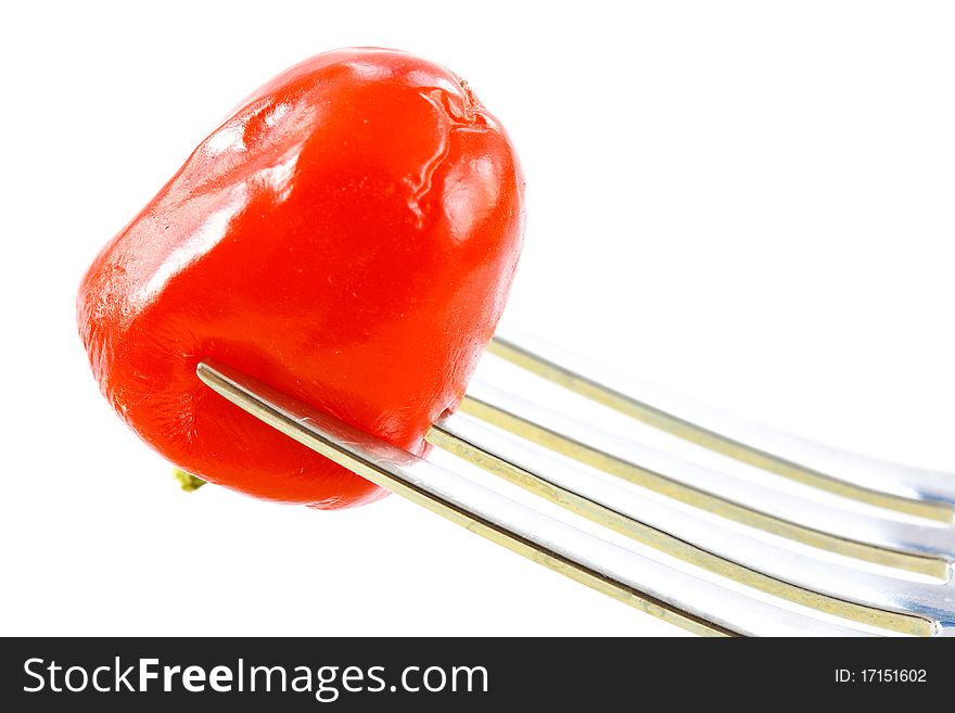 Red pepper on a fork on a white background