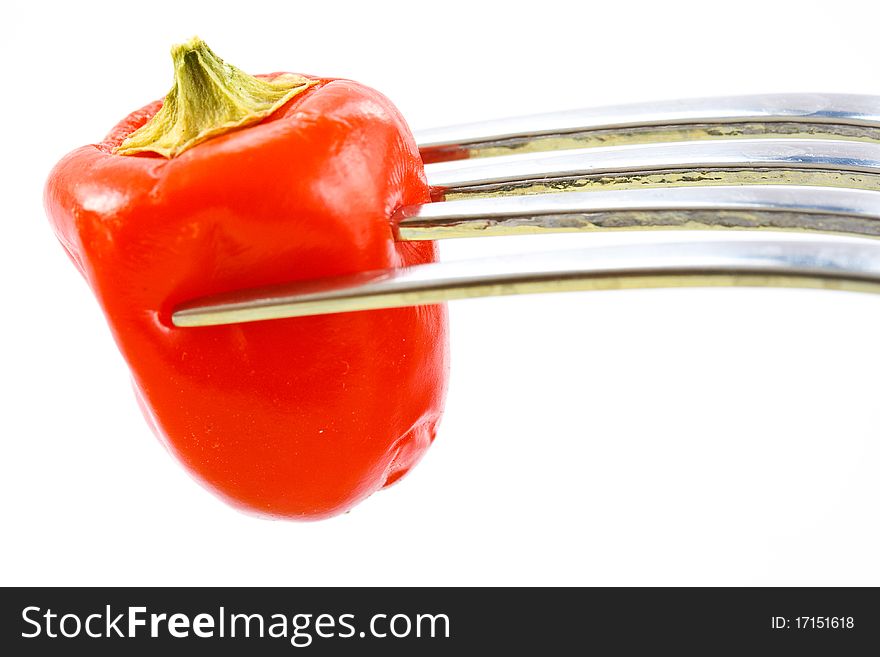 Red pepper on a fork on a white background