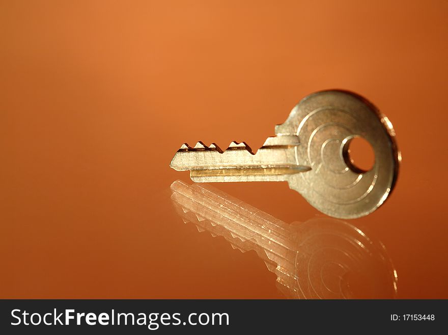 Closeup of yellow metal key lying on glass background