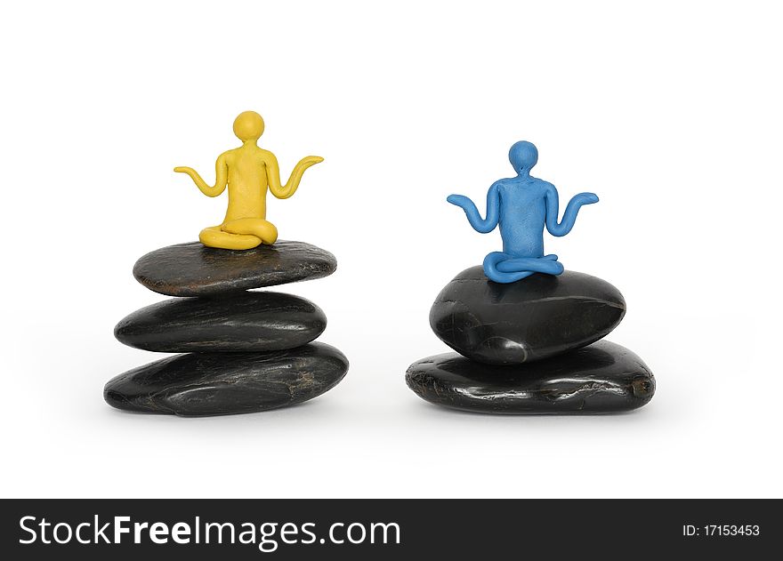 Two color plasticine men meditating in lotus position on black balancing stones. Isolated with clipping path on white background. Two color plasticine men meditating in lotus position on black balancing stones. Isolated with clipping path on white background