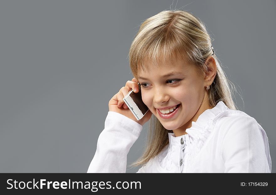 Portrait of a beautiful little girl with blond hair, talking on a mobile phone. Portrait of a beautiful little girl with blond hair, talking on a mobile phone