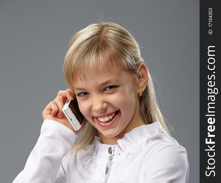 Portrait of a beautiful little girl with blond hair, talking on a mobile phone. Portrait of a beautiful little girl with blond hair, talking on a mobile phone