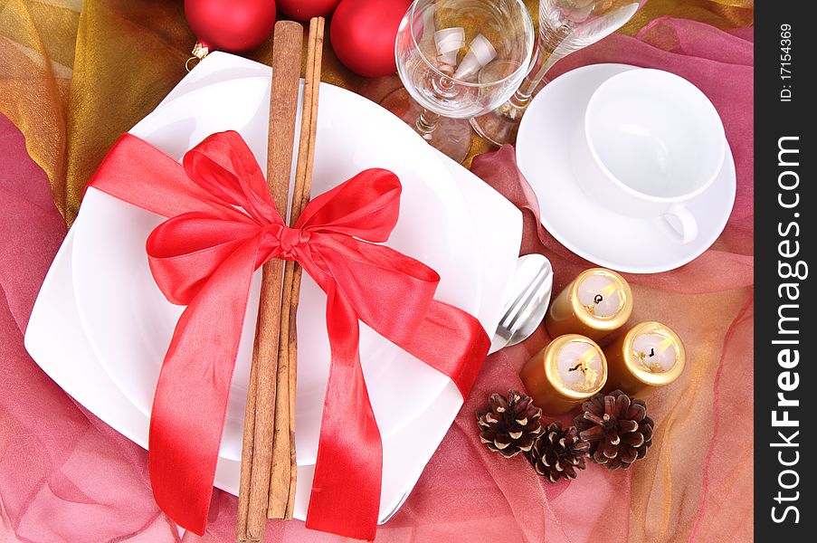 Christmas tableware, decorated with cinnamon sticks, ribbon, christmas balls, candles and cones in close up