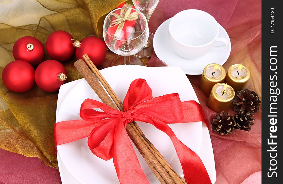 Christmas or New Year's setting, plate decorated with cinnamon sticks and ribbon with christmas balls, candles and cones in close up