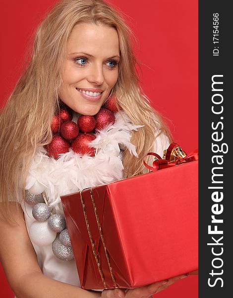 blond woman with some christmas balls around the neck holding a present. blond woman with some christmas balls around the neck holding a present