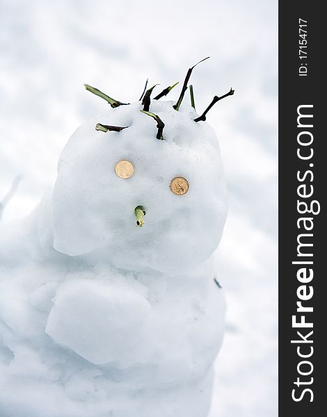 Snowman on a background of snow with coins place the eye