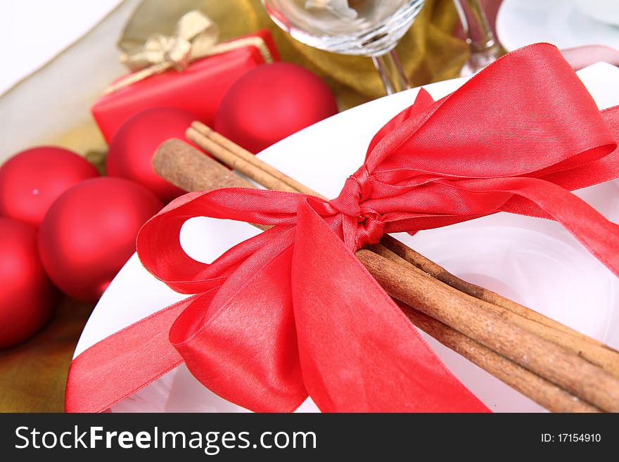 Christmas tableware, decorated with cinnamon sticks, ribbon, christmas balls and cones in close up