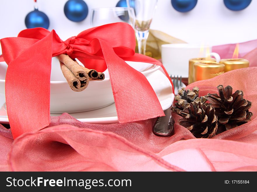 Christmas tableware, decorated with cinnamon sticks, ribbon, christmas balls, candles and cones in close up