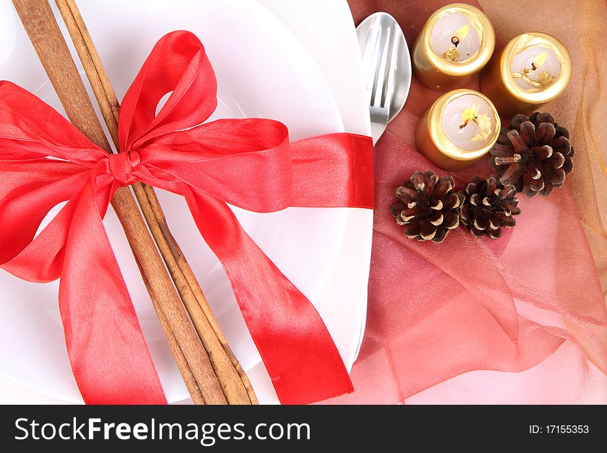 Christmas tableware, decorated with cinnamon sticks, ribbon, burning candles and cones