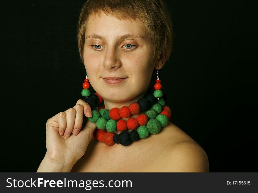 Young woman with bare shoulders in her wearing a necklace and earrings made of wool. Ethnos. Young woman with bare shoulders in her wearing a necklace and earrings made of wool. Ethnos
