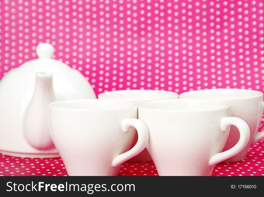 A set of white cups and a teapot on a crimson background