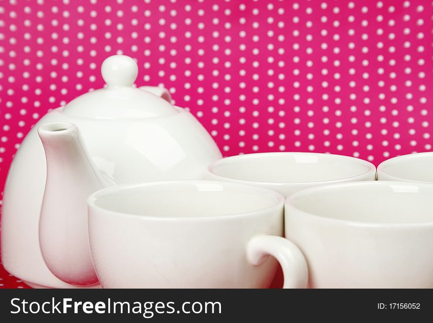 A set of white cups and a teapot on a crimson background