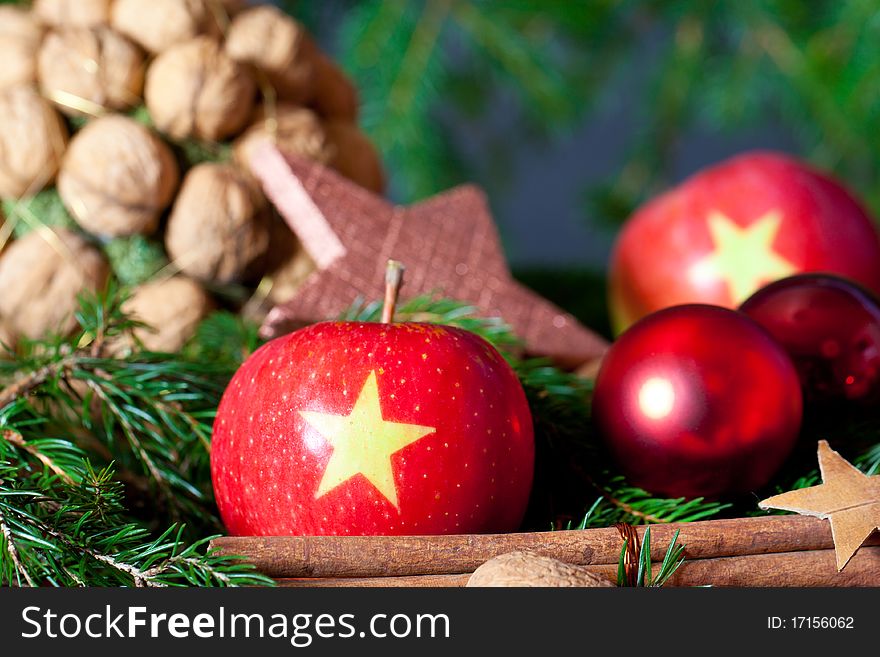 Two red Apples with a Christmas Star on it on a decoration with nuts, cinnamon and a star. Two red Apples with a Christmas Star on it on a decoration with nuts, cinnamon and a star