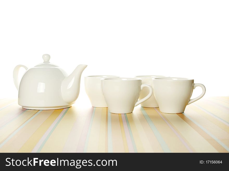 A set of four white cups and a teapot on a light striped background. The upper part of the photo is isolated