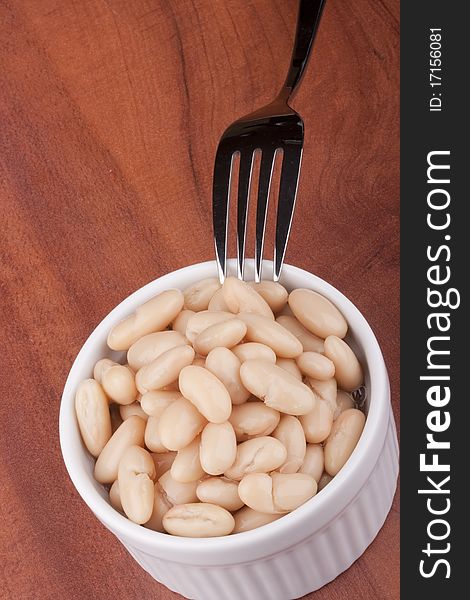 White canned beans in a white ceramic bowl with a fork. White canned beans in a white ceramic bowl with a fork.