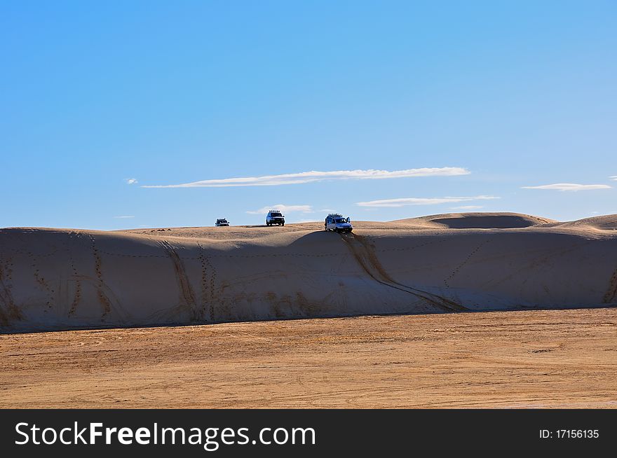 Several off-road vehicles in car safari, the first car in a steep descent from the hill. Several off-road vehicles in car safari, the first car in a steep descent from the hill