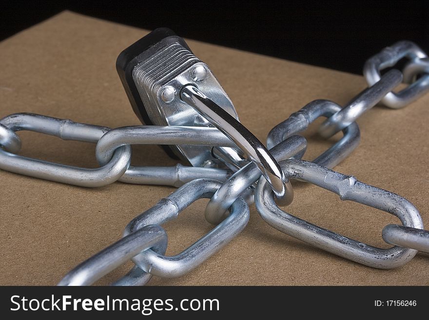 Metal lock and chain on a brown background.