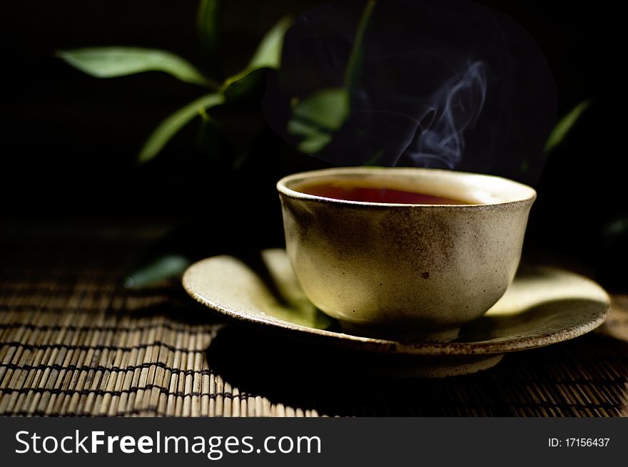 Cup of tea and twig with dark background