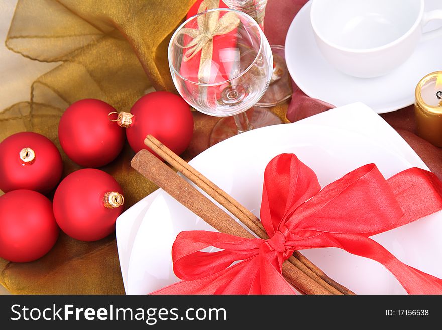 Christmas tableware, decorated with cinnamon sticks, ribbon, christmas balls and cones in close up. Christmas tableware, decorated with cinnamon sticks, ribbon, christmas balls and cones in close up