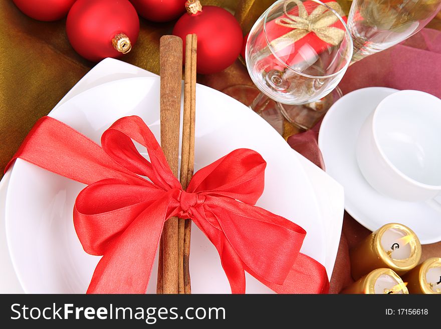 Christmas or New Year's setting, plate decorated with cinnamon sticks and ribbon with christmas balls, candles and cones in close up