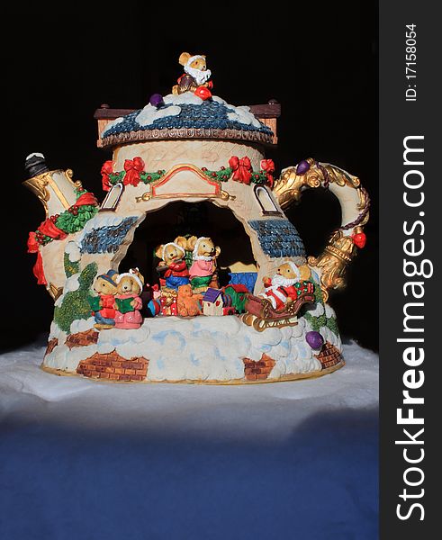 A colourful china teapot with miniature bear caricatures playing instruments and singing, surrounded by presents and toys. A colourful china teapot with miniature bear caricatures playing instruments and singing, surrounded by presents and toys.