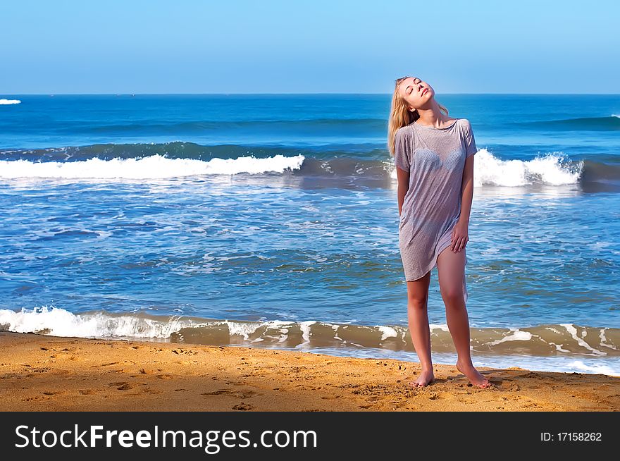 A young beautiful blond girl is staying near the ocean in the morning. A young beautiful blond girl is staying near the ocean in the morning