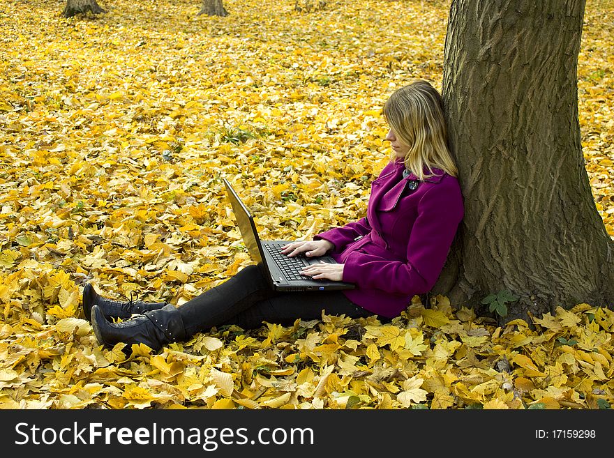 Girl with a laptop near a tree