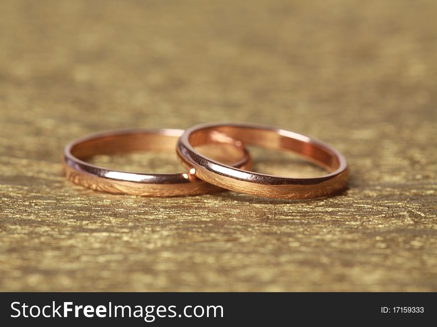 Two wedding rings on golden background