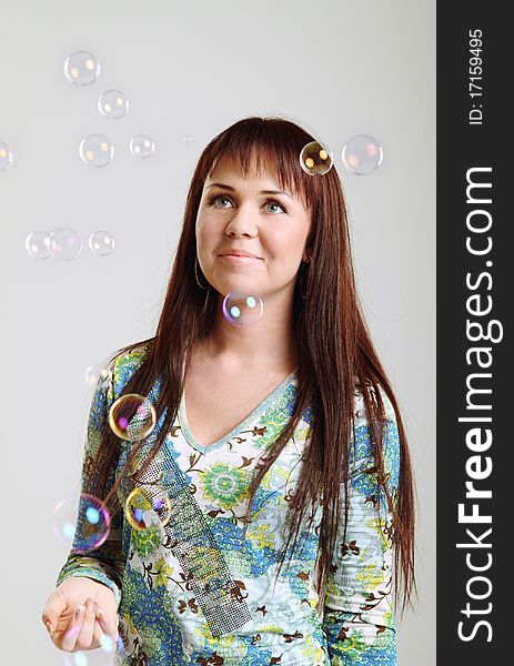 Smiling brunette girl looking at soap  bubbles