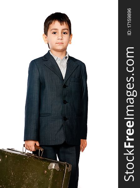 Boy in a suit and carrying a suitcase on a light background
