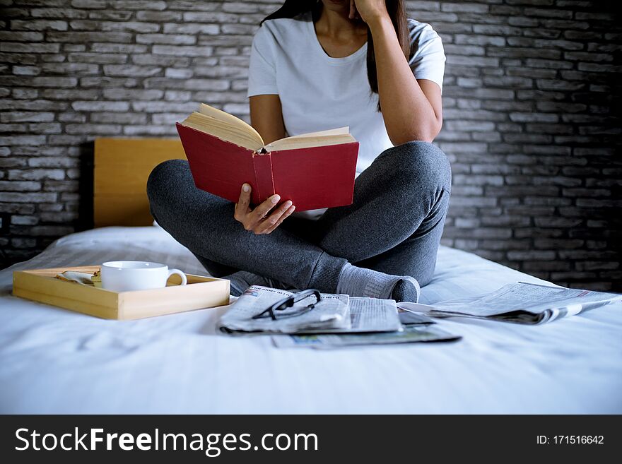 Happy woman reading a book and relaxing comfortably at home.