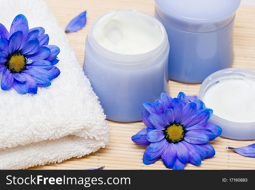 Spa essentials, cream and towel with blue flowers