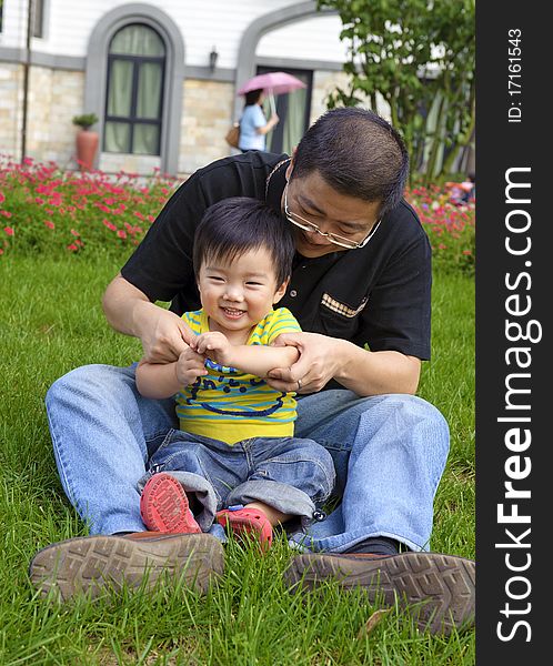 Happy baby is playing with his father on lawn