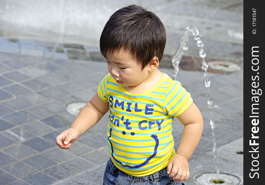 A cute baby is playing fountain. A cute baby is playing fountain