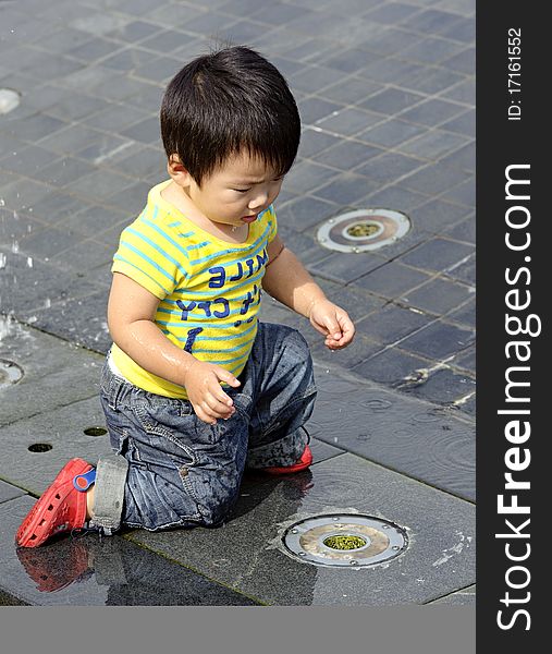 A cute baby is playing fountain. A cute baby is playing fountain