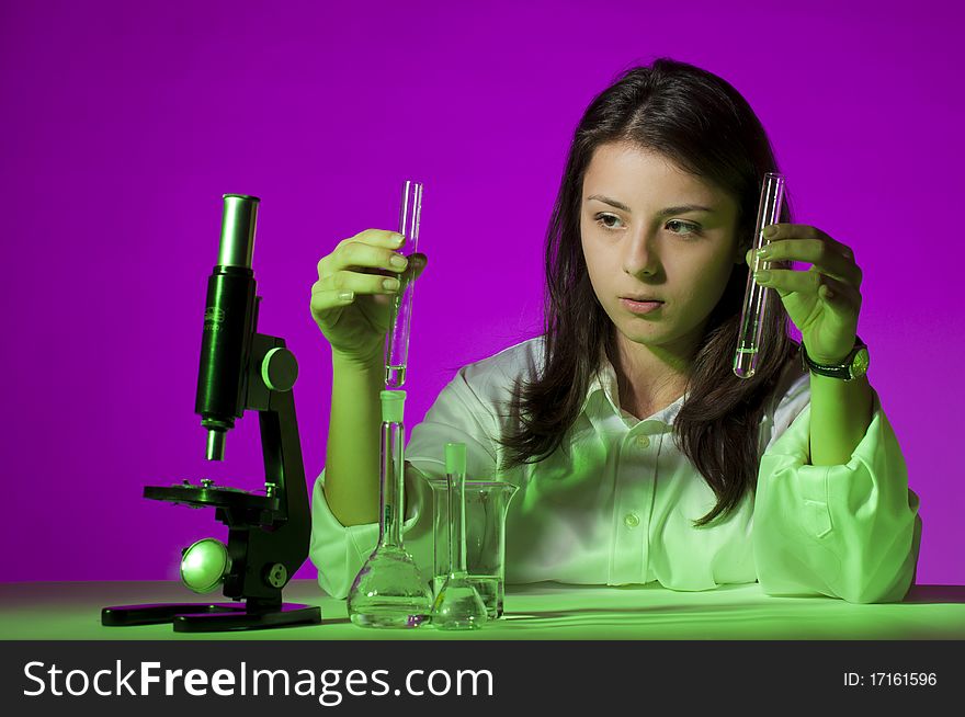 Young school girl playing with tubes and a microscope. Young school girl playing with tubes and a microscope