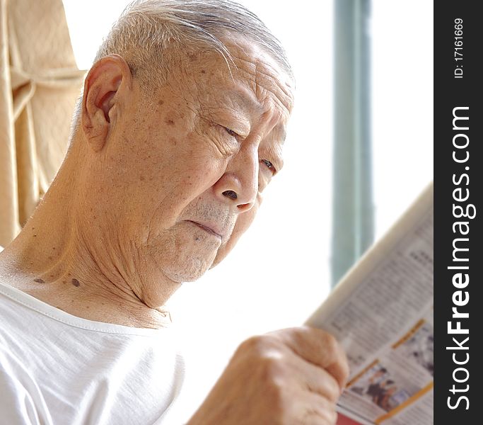 A senior man is reading newspaper